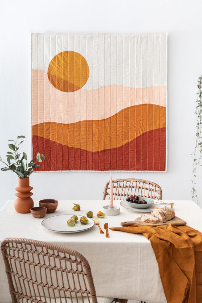 studio photoshoot in burnt orange, pink and natural tones. quilted wall hanging